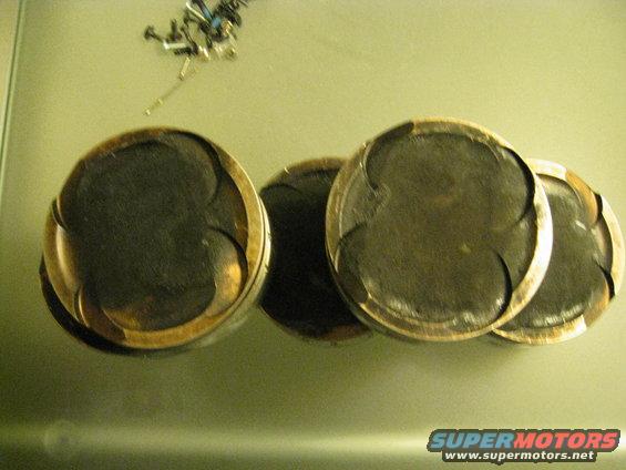 Four used pistons with visible wear marks