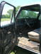 1975 Ford F-250 - Interior view of a Ford truck, revealing the dashboard, steering wheel, and a worn seat, with the driver's door removed.