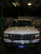 1975 Ford F-250 - This white Ford F-Series truck is parked indoors, showing its front grille and headlights.