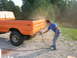 1975 Ford F-250 - A person spray paints the rear quarter panel of an orange 1975 Ford F-250 pickup truck.
