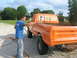 1975 Ford F-250 - Man spray painting the rear of an orange 1975 Ford F-250 pickup truck.