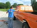 1975 Ford F-250 - Man spray painting an orange 1975 Ford F-250 pickup truck, masking the rear window with newspaper.