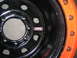 1975 Ford F-250 - Close-up of a black truck wheel with an orange outer rim, showing a MRW brand sticker.