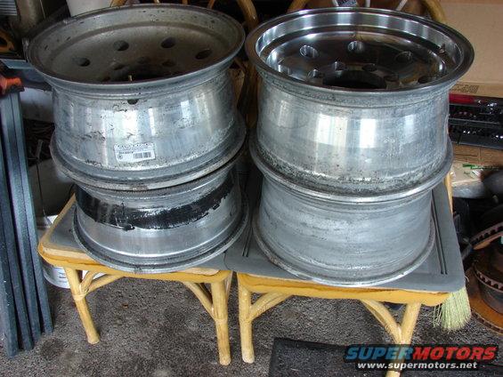 Four stacked aluminum wheels with visible wear and a label on one