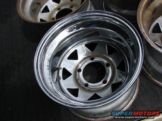 close-up of a chrome wheel with triangular cutouts, another wheel visible behind it
