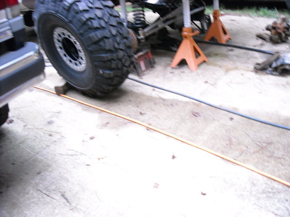 Truck chassis on jack stands with a large off-road tire visible
