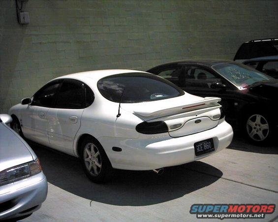 White sedan with a spoiler and a license plate reading SCE 860 parked next to a black car