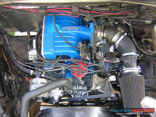 Engine bay showing a blue Edelbrock intake manifold, alternator, and air filter. Text on manifold reads 'Edelbrock'