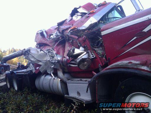 Heavily damaged red semi-truck cab, front quarter view
