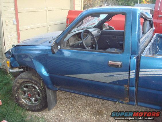 Blue 1991 Toyota Tacoma pickup truck, driver's side view, damaged front fender and windshield