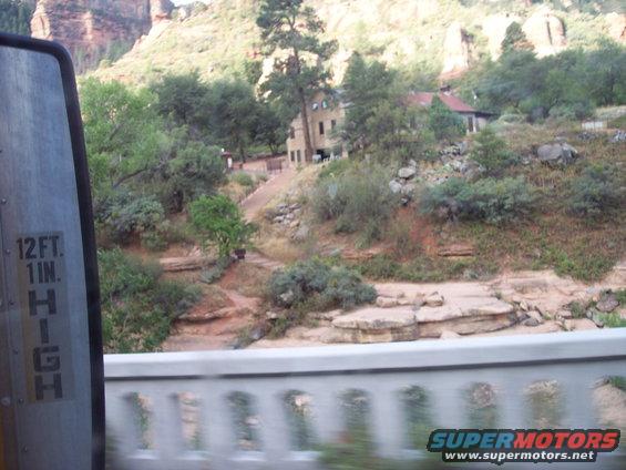 View of buildings on a hillside with mountains in background. Side mirror with height restriction visible