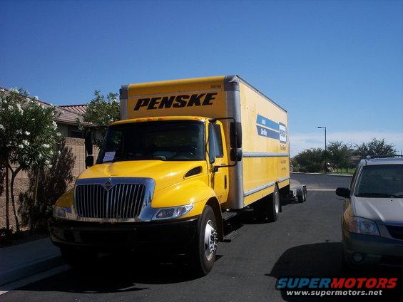 Yellow Penske box truck parked next to a silver SUV