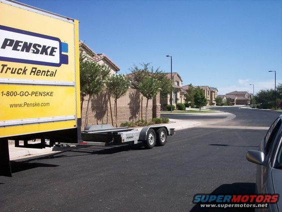 Penske truck with car trailer attached, parked on a suburban street