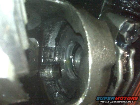 Close-up of a greasy differential housing with visible gears and bolts