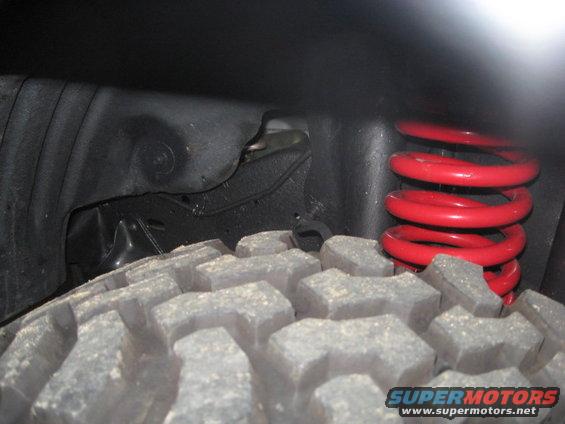 Close-up of a red coil spring and tire tread in a wheel well