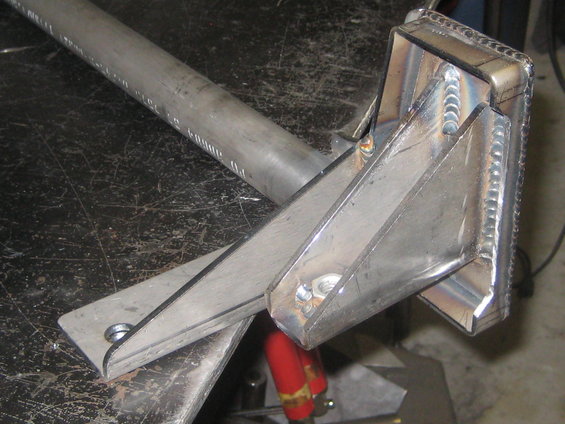Welded metal bracket with a tubular extension, resting on a dark, scratched surface