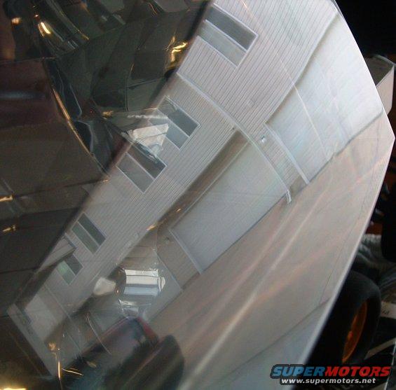 Reflection of a house with multiple windows on a shiny, curved surface