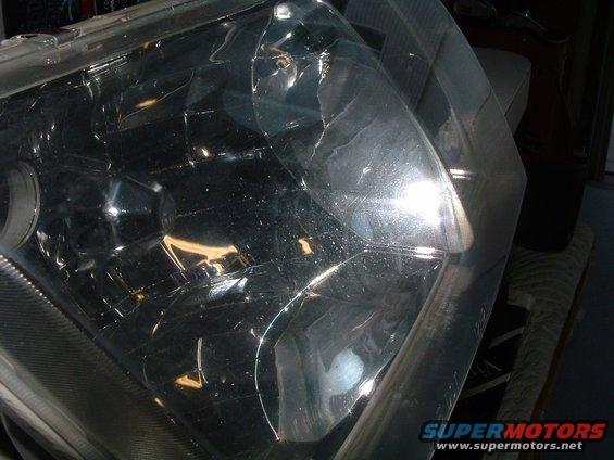 Headlight assembly with cracked clear plastic lens and visible internal reflectors