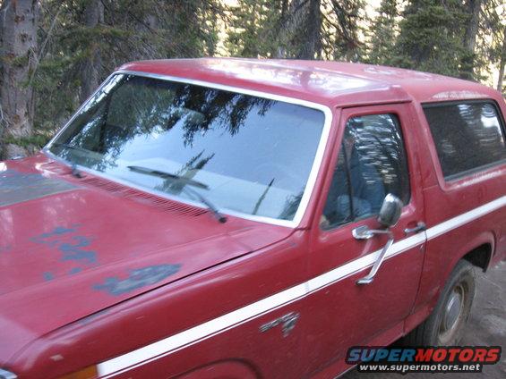 Red Ford Bronco with white stripe, hood paint faded, parked outdoors