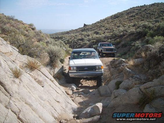 White 1987 Ford Bronco on rocky trail with another SUV behind
