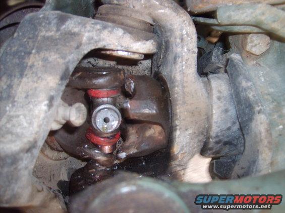 Close-up of a worn ball joint with red bushings and grease