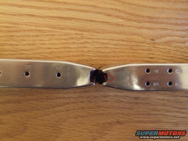 Close-up of a firearm magazine with numbered holes, showing damage