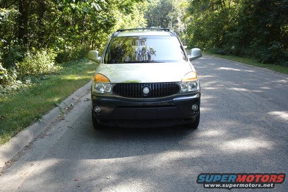Front view of a 2002 Buick Rendezvous parked on a paved road with trees on either side