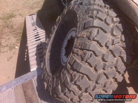 Close-up of a large, aggressive off-road tire with a beadlock wheel, resting on a ramp