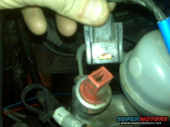 Engine bay with gray and red electrical connectors, blue wire, and a light blue reservoir