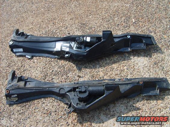 Two black automotive plastic parts with metal components on gravel