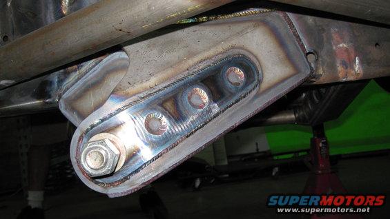 Welded steel suspension bracket with three bolt holes and a large hex bolt, attached to a vehicle frame