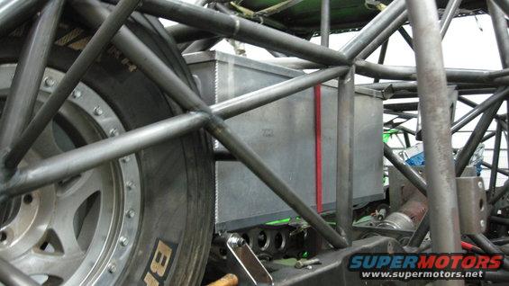 Close-up of a custom roll cage with a fuel cell and tire visible