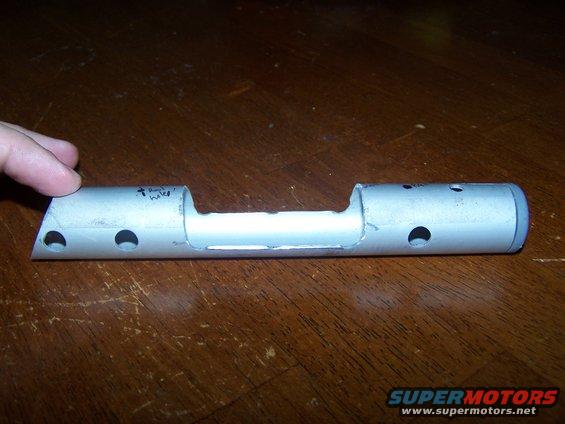 Metal part with holes and handwritten text
