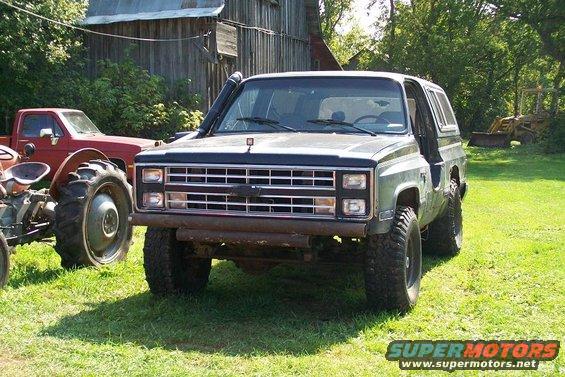 Black Chevrolet K5 Blazer with snorkel, lifted suspension, and aftermarket bumper parked on grass