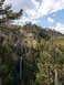 2006 Ford E350 - A tall waterfall plunges into a narrow canyon, framed by cliffs and dense evergreen trees.