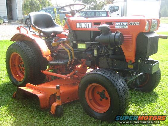 Kubota B7100 4WD tractor with mower deck. Visible text: KUBOTA, B7100 4WD, SUPER MOTORS