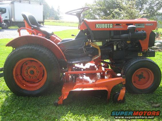 Orange Kubota tractor with a mower deck, viewed from the side
