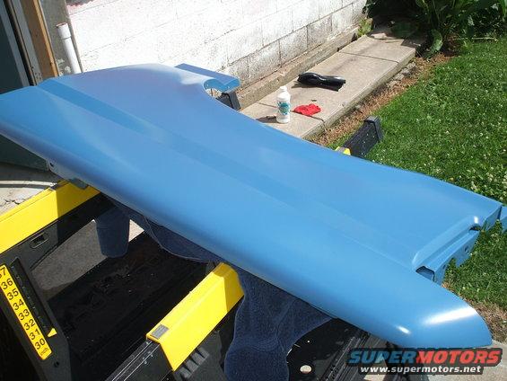 Blue car fender on a workbench, with cleaning supplies nearby