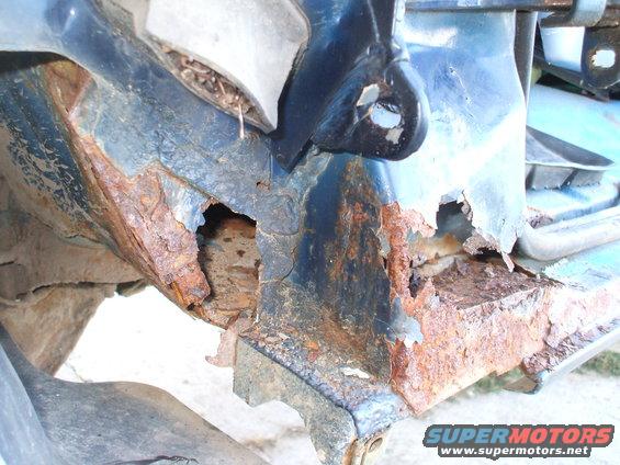 Close-up of heavily rusted and corroded vehicle frame with holes
