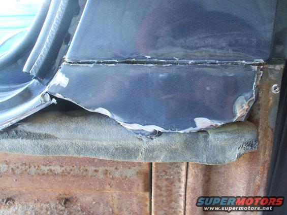 Damaged blue car panel over rusted metal