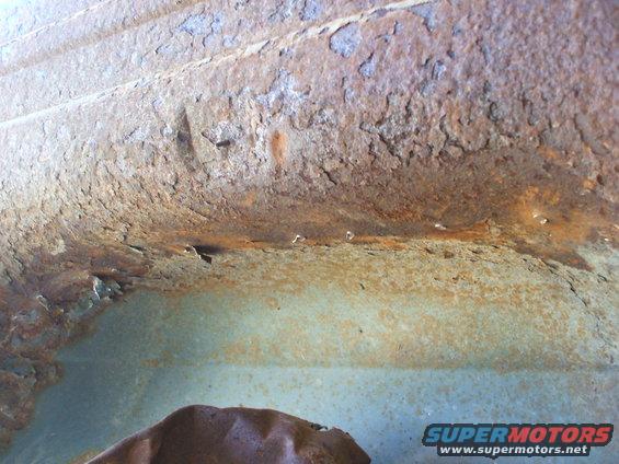 heavily rusted metal panel with peeling paint and some pitting