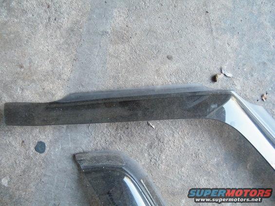 Black plastic and chrome car trim pieces on concrete
