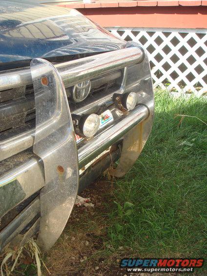 Front grille of a Toyota truck with a chrome bull bar and two fog lights. A "Super Motors" watermark is visible at the bottom right