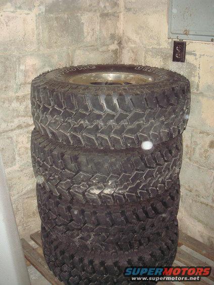 Stack of four off-road tires with visible tread pattern and sidewall text