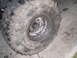 1984 Ford Bronco II - A close-up shows a heavily used off-road tire and wheel assembly with mud caked on the tread.