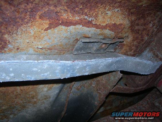 rusted metal frame of a vehicle, showing significant corrosion and structural components