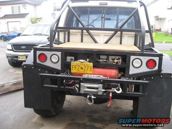 Rear view of a custom truck bed with winch, fuel tank, and Alaska license plate FFZ 273