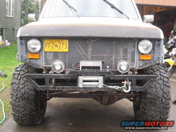Front view of a modified Ford F-Series truck with large off-road tires, a winch, and an Alaska license plate