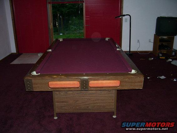 Pool table with purple felt and wooden frame