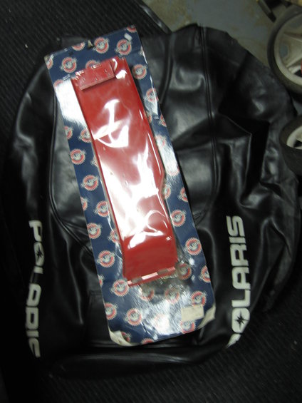 Black Polaris seat cover with a red part in blue and white packaging on top